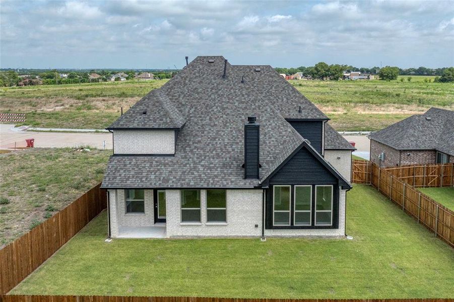 Back of house with roof with shingles, a fenced backyard, a patio, and brick siding