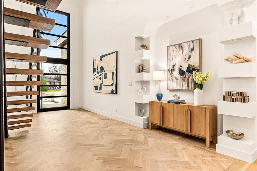 Two story ceilings and herringbone wood floors immediately set the scale of the home, creating a sense of openness that feels dramatic yet easy to settle into