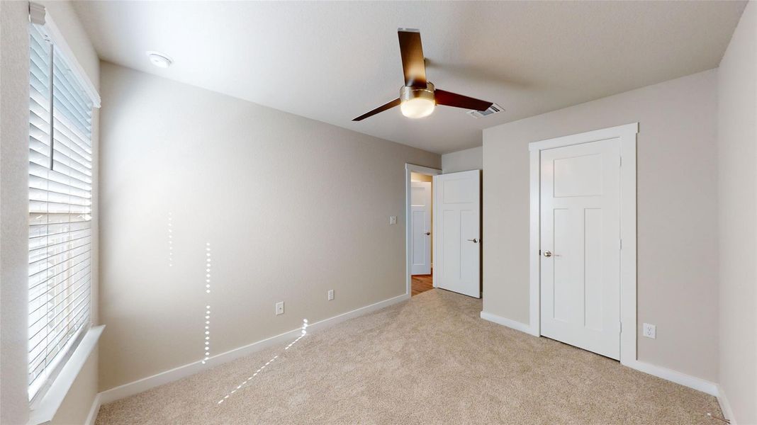 A well-lit bedroom features plush carpeting and a modern ceiling fan for ultimate comfort. A well-lit bedroom features plush carpeting and a modern ceiling fan for ultimate comfort.