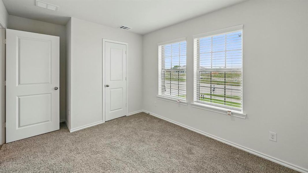 Bright interior space featuring two large windows with blinds, light gray wall paint, and gray textured carpet