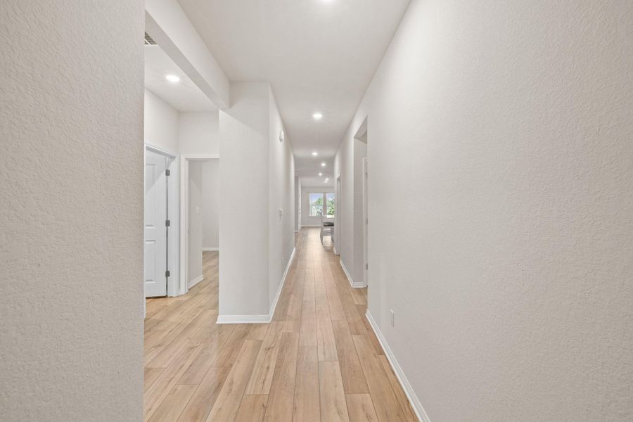 Corridor with a textured wall, light wood-type flooring, and recessed lighting Corridor with a textured wall, light wood-type flooring, and recessed lighting