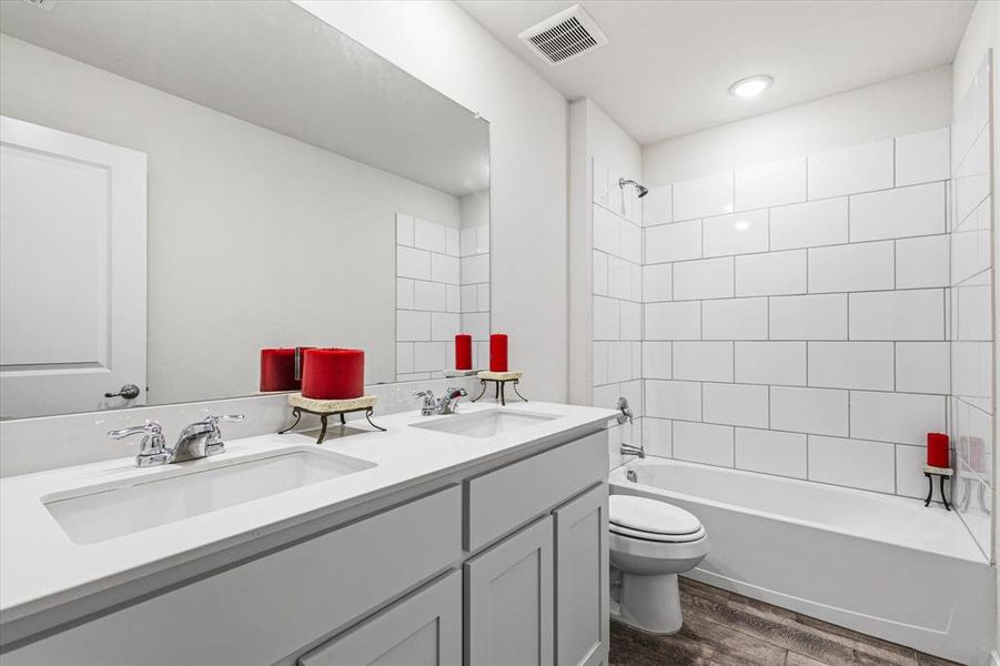 Secondary bathroom featuring dual sinks for convenience and functionality.