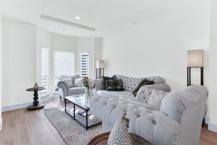 Living area featuring light wood-style floors and a tray ceiling Living area featuring light wood-style floors and a tray ceiling