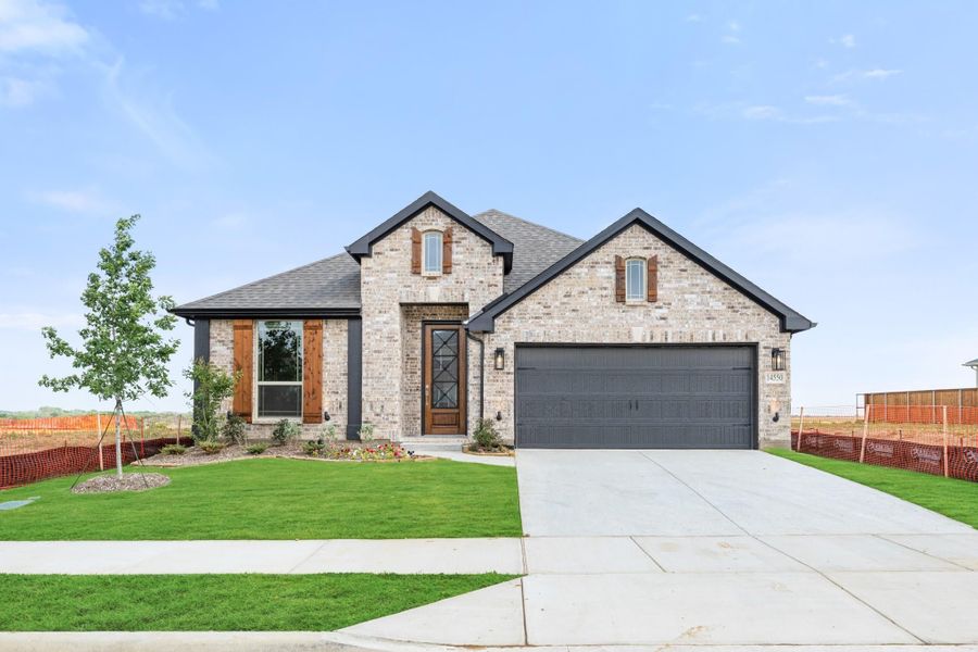 Single-story brick home with dark roof, two-car garage, wood shutters, and green front lawn Single-story brick home with dark roof, two-car garage, wood shutters, and green front lawn
