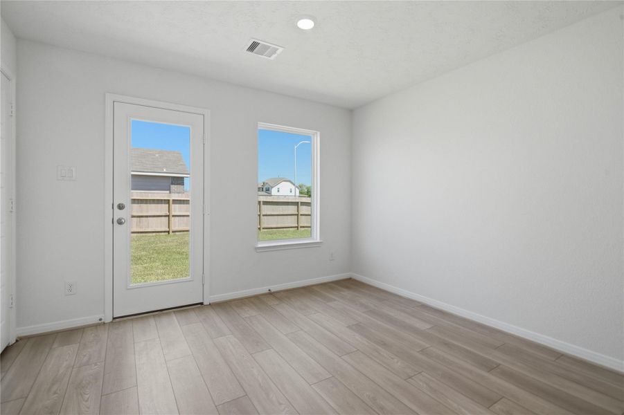 Start your day with a warm cup of coffee and quality time in this charming breakfast nook! Highlights include a large window, custom neutral paint, vinyl plank flooring, recessed lighting, high ceilings, and a convenient door leading to the backyard.