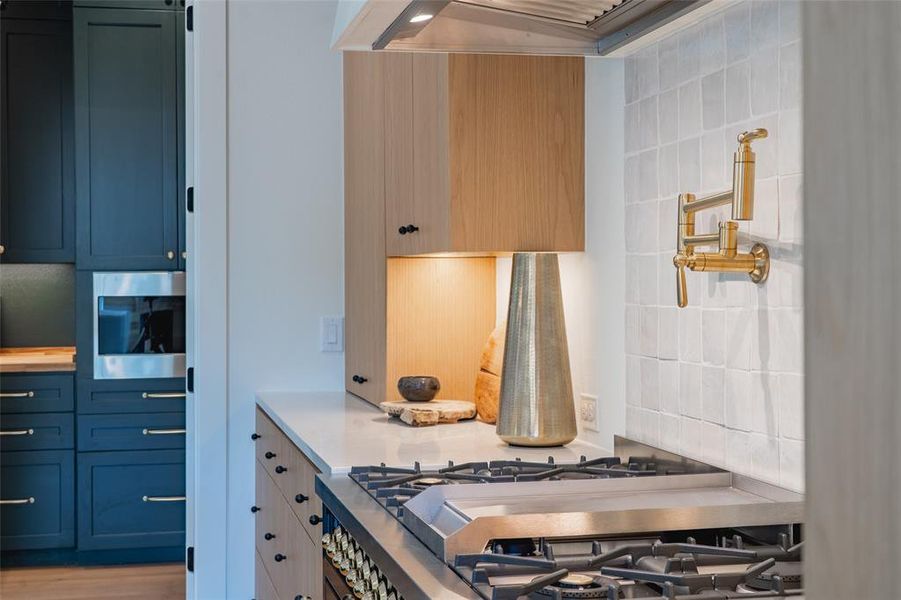 Kitchen with light hardwood / wood-style floors, decorative backsplash, blue cabinets, and stainless steel appliances