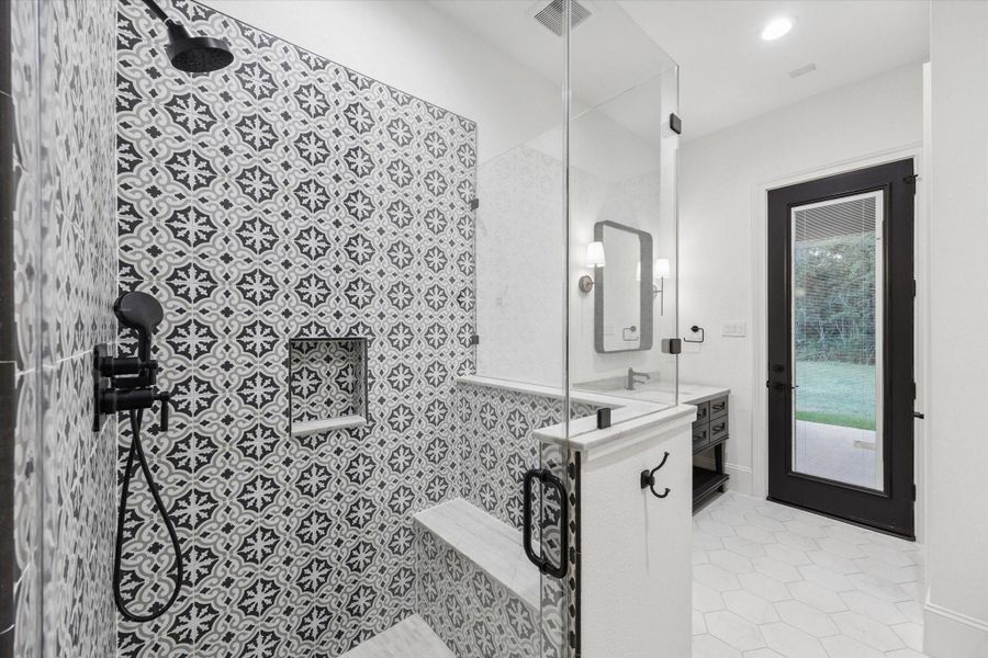 The full pool bathroom provides convenient access from both the interior and the covered patio, making it ideal for future pool use and outdoor entertaining. A striking patterned shower wall creates a dramatic designer focal point, while the walk-in shower includes built-in niches and carefully selected fixtures. Clean architectural lines, abundant natural light, and direct exterior access combine style and practicality in a space thoughtfully designed to support the home’s indoor-outdoor lifestyle.