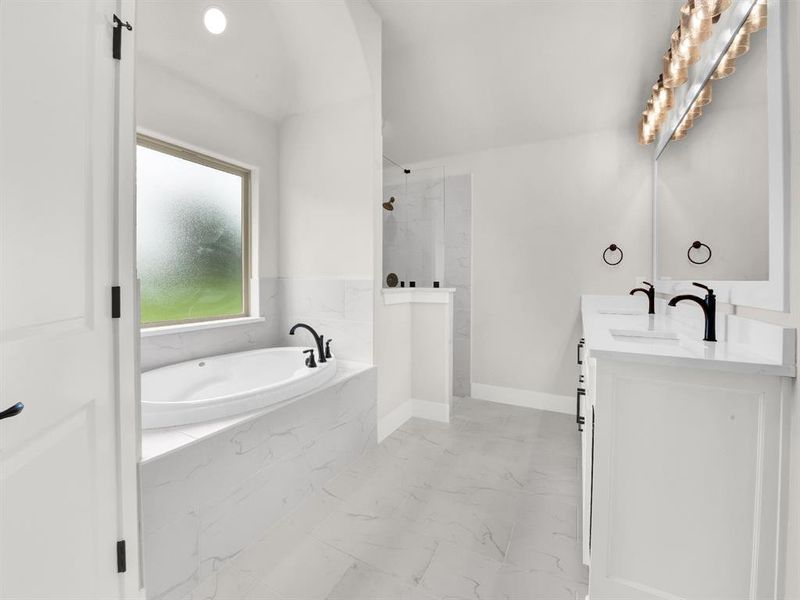 Full bath featuring a bath, a marble finish shower, double vanity, light marble finish floors, and recessed lighting