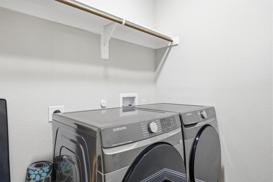 Laundry room featuring washing machine and clothes dryer and a textured wall