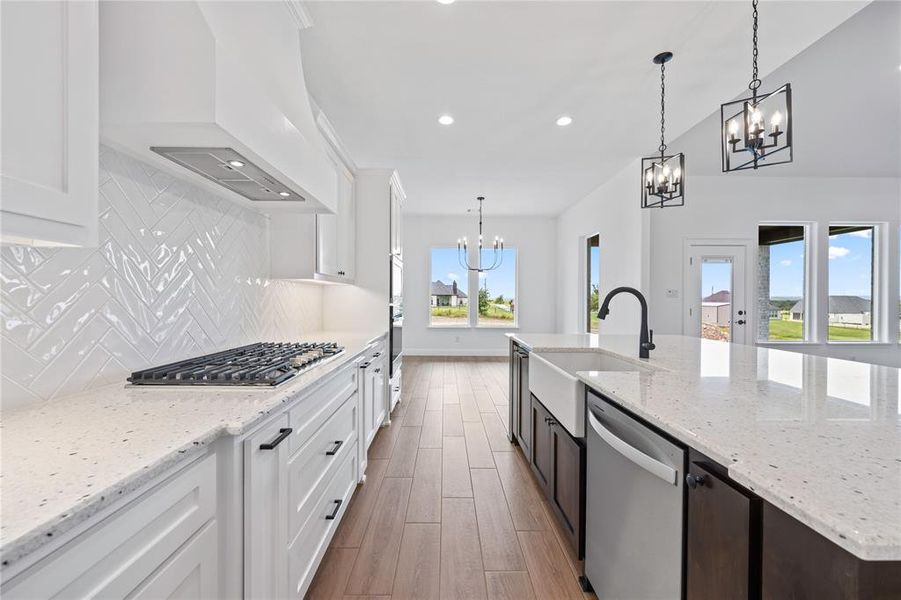 Kitchen featuring stainless steel appliances, a chandelier, custom range hood, wood finished floors, and decorative backsplash