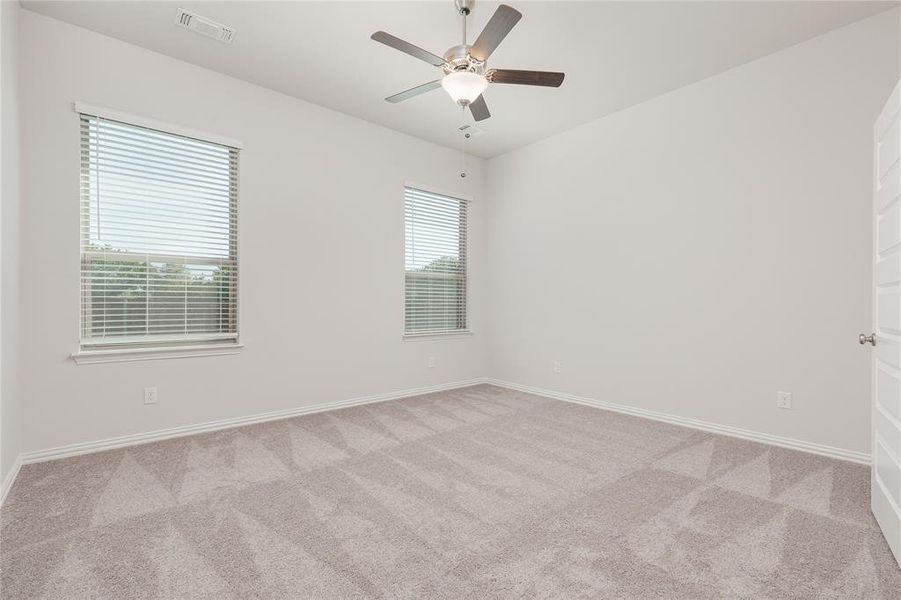 Carpeted spare room featuring ceiling fan and a healthy amount of sunlight