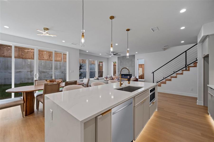 Kitchen featuring appliances with stainless steel finishes, decorative light fixtures, a kitchen island with sink, and sink