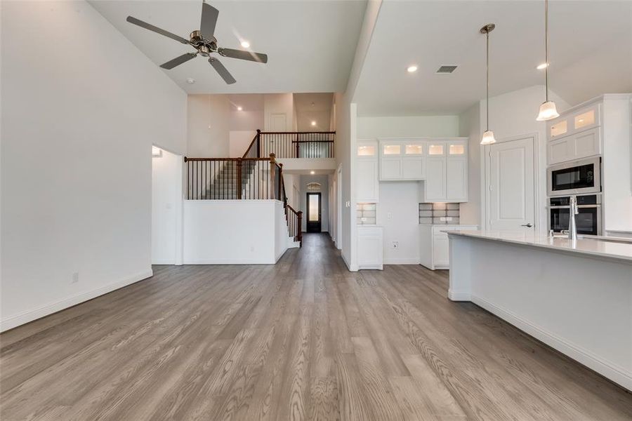 Kitchen featuring light hardwood / wood-style flooring, stainless steel oven, white cabinets, a high ceiling, and black microwave