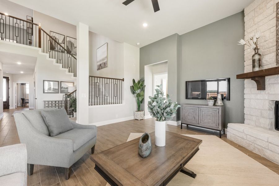 Open living room with high ceilings, stone fireplace, wood coffee table, and staircase visible in background