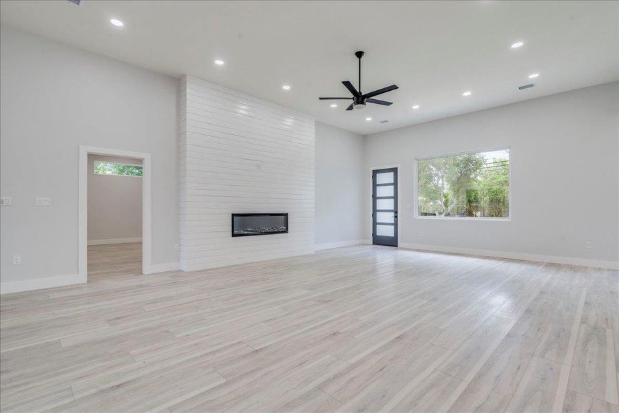 Living room with healthy amount of natural light, a fireplace, recessed lighting, ceiling fan, and light wood finished floors