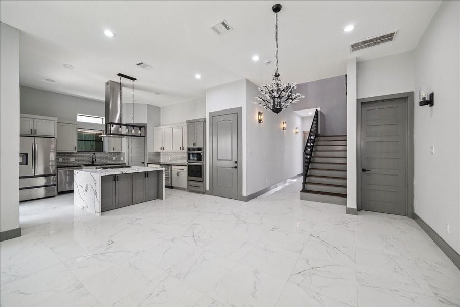 Tile floors extend through the open living area, drawing the eye toward the modern kitchen and upstairs retreat.