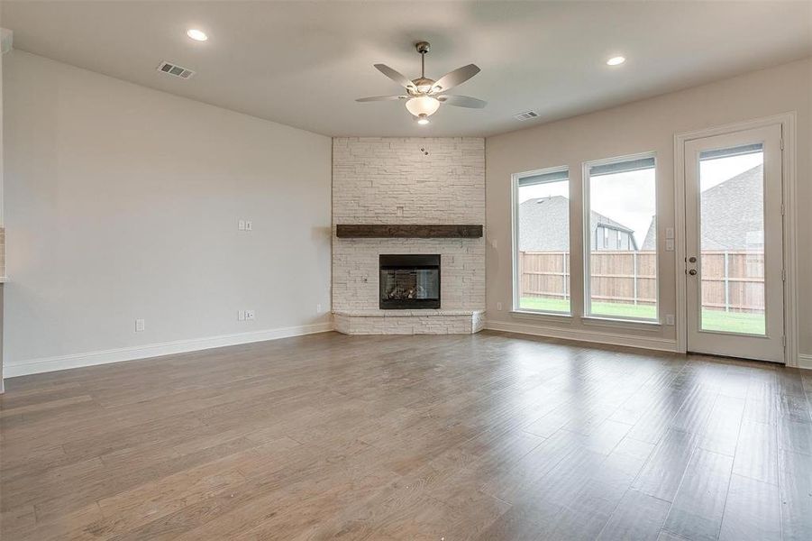 Unfurnished living room featuring wood-type flooring, ceiling fan, and a fireplace