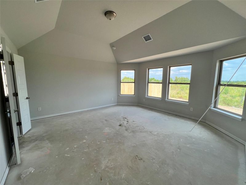 Empty room featuring lofted ceiling and unfinished concrete floors