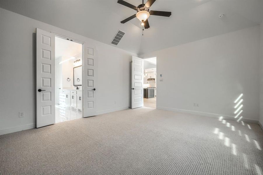 Unfurnished bedroom with light carpet, visible vents, baseboards, and vaulted ceiling