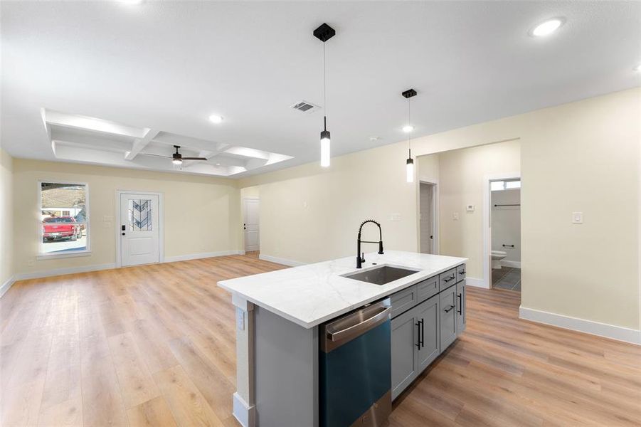 Kitchen with beamed ceiling, sink, hanging light fixtures, coffered ceiling, and stainless steel dishwasher