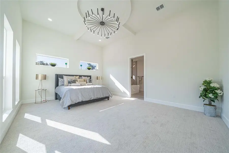 Carpeted bedroom featuring beam ceiling, ensuite bath, and recessed lighting