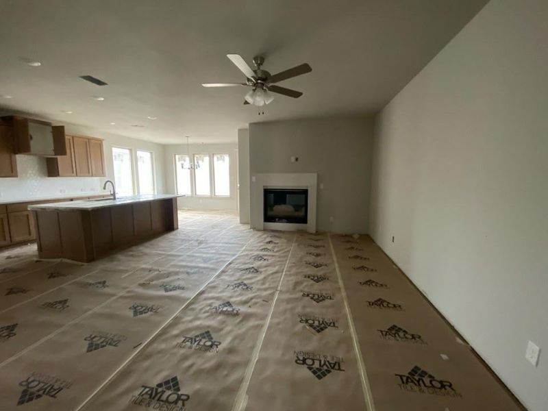 Spacious open-concept living area featuring a fireplace with a white mantel, a ceiling fan, and recessed lighting