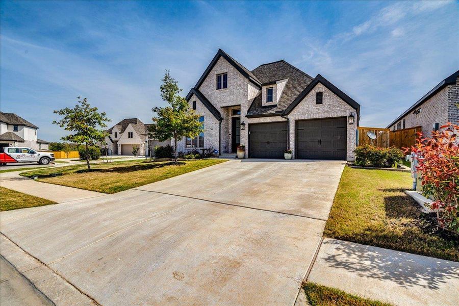 French provincial home with stone siding, a front yard, driveway, a garage, and a residential view