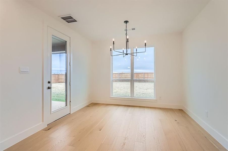 Unfurnished dining area with an inviting chandelier and light hardwood / wood-style flooring