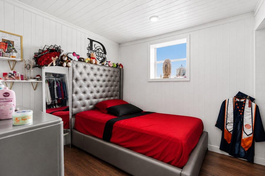 Well-lit sleeping quarters with a richly upholstered headboard and warm wood-look flooring.