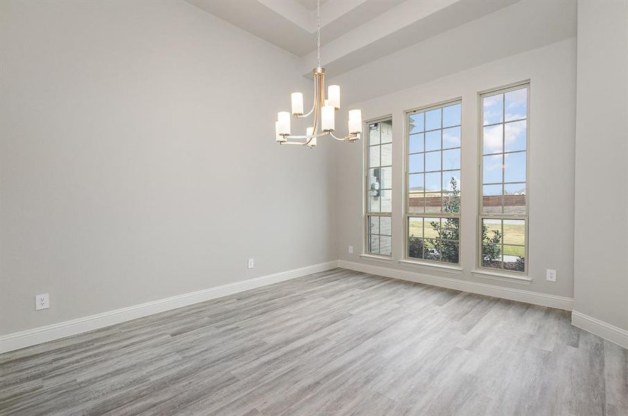 Empty room with light wood-type flooring and a chandelier