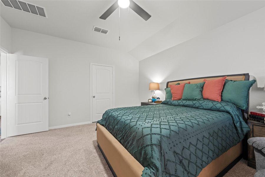 Comfortable bedroom with plush carpeting and a modern ceiling fan for optimal relaxation.