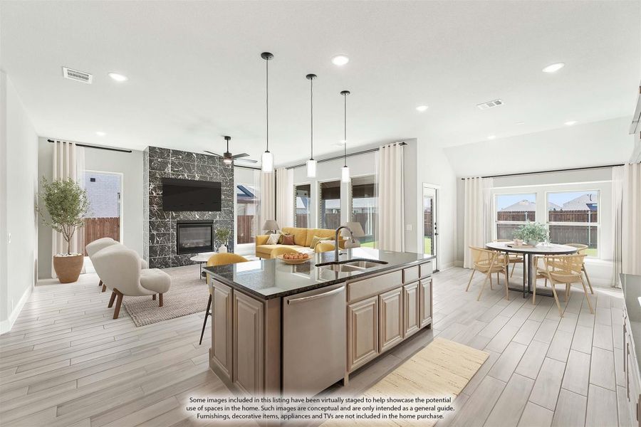Open-concept kitchen with large island, pendant lights, and views into living and dining areas with stone fireplace Open-concept kitchen with large island, pendant lights, and views into living and dining areas with stone fireplace