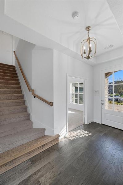 Doorway to outside with wood-type flooring, plenty of natural light, a chandelier, and stairs