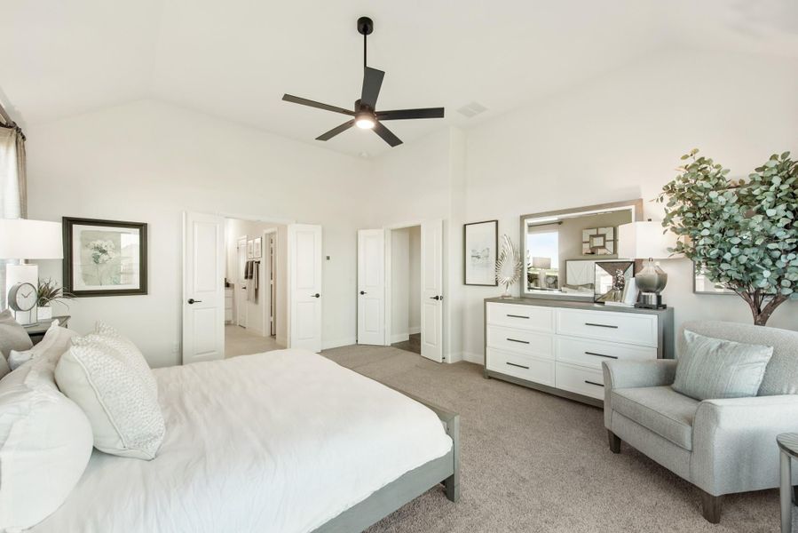 Master bedroom with vaulted ceiling, ceiling fan, white dresser, and carpet flooring with ensuite bathroom access