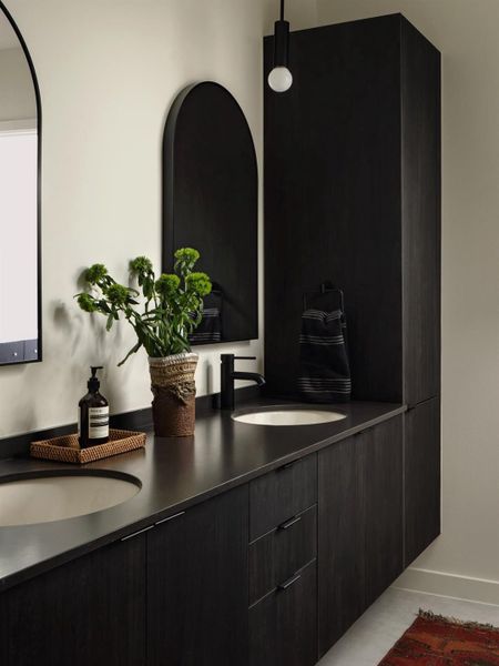Sleek dark cabinetry paired with stone countertops defines this modern double vanity. Sleek dark cabinetry paired with stone countertops defines this modern double vanity.