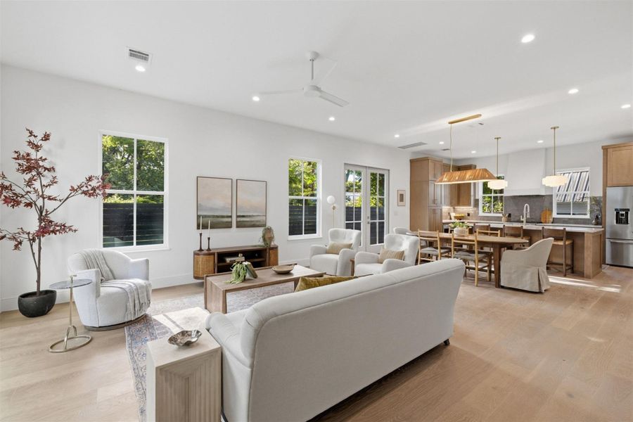 An airy living space with hardwood floors seamlessly flows into a well-appointed kitchen, ideal for modern living.