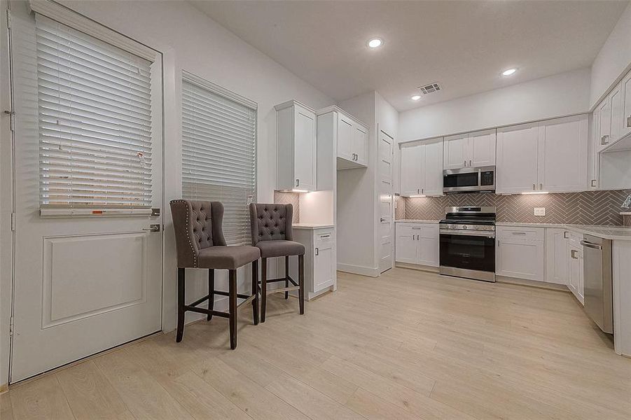 The beautiful quartz countertops are elegantly showcased along with the subway tile backsplash laid in a herringbone pattern. The cabinets have under cabinet lighting and outlets to enhance the functionality of this kitchen.