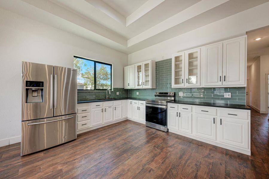 Rich wood floors and recessed ceilings frame a modern culinary space with clean white cabinetry.