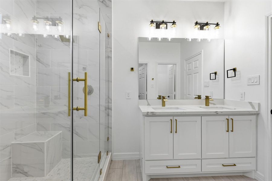 Primary bathroom with double sink vanity, large mirror, and frameless glass walk in shower.