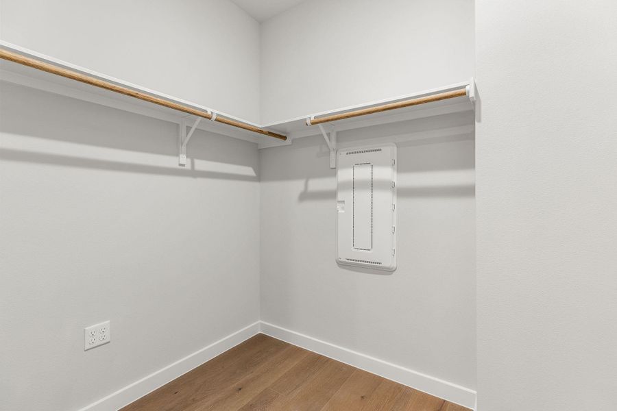 Walk in closet with electric panel and wood finished floors