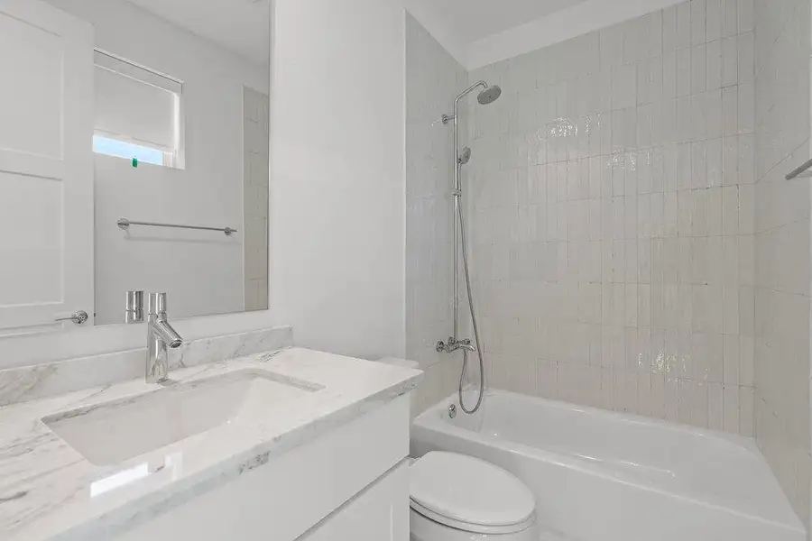 A well-appointed bathroom features a single vanity with stone counters and a spacious bathtub and shower combination. A well-appointed bathroom features a single vanity with stone counters and a spacious bathtub and shower combination.