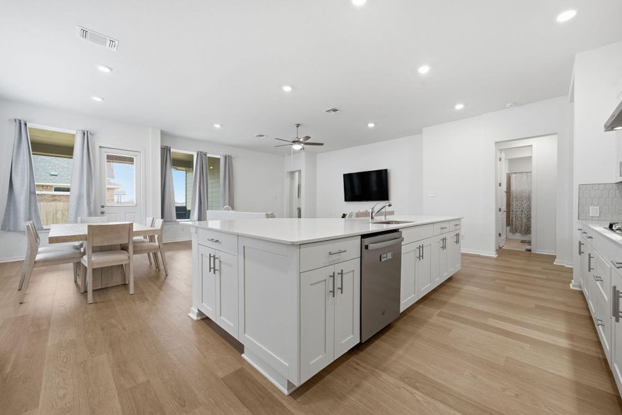 Kitchen featuring a large island, white cabinetry, light wood finished floors, stainless steel dishwasher, and recessed lighting