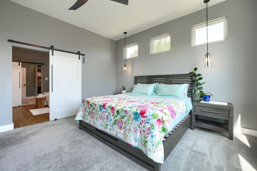 Bedroom featuring carpet, a ceiling fan, and a barn door Bedroom featuring carpet, a ceiling fan, and a barn door