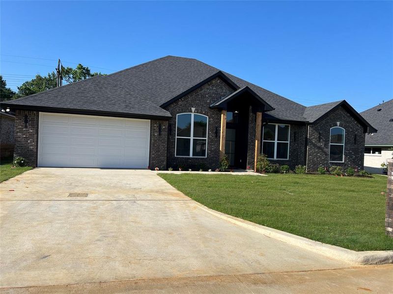 View of front facade featuring driveway, a garage, a front yard, and brick siding