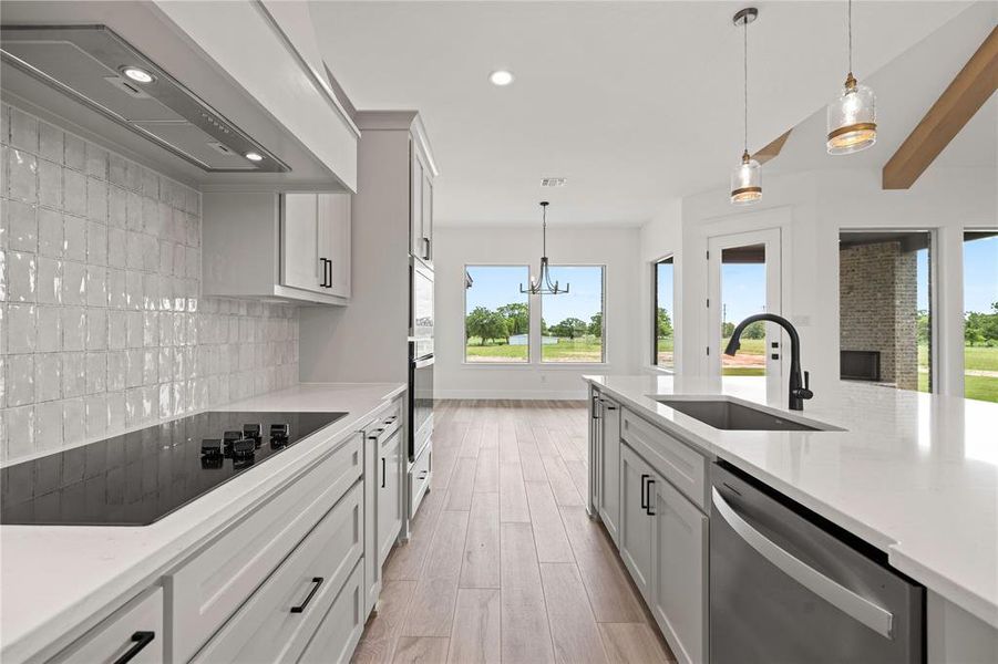 Kitchen with pendant lighting, premium range hood, stainless steel appliances, light stone countertops, and recessed lighting Kitchen with pendant lighting, premium range hood, stainless steel appliances, light stone countertops, and recessed lighting