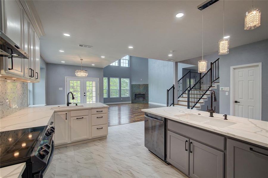 Kitchen featuring light hardwood / wood-style flooring, hanging light fixtures, stainless steel dishwasher, electric range oven, and light stone countertops