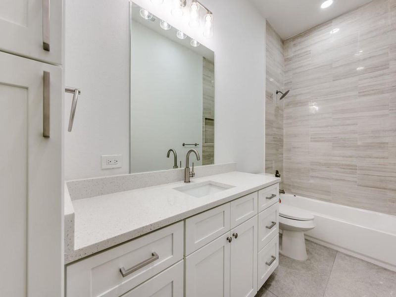 Full bathroom with vanity, tile patterned floors, toilet, and tiled shower / bath