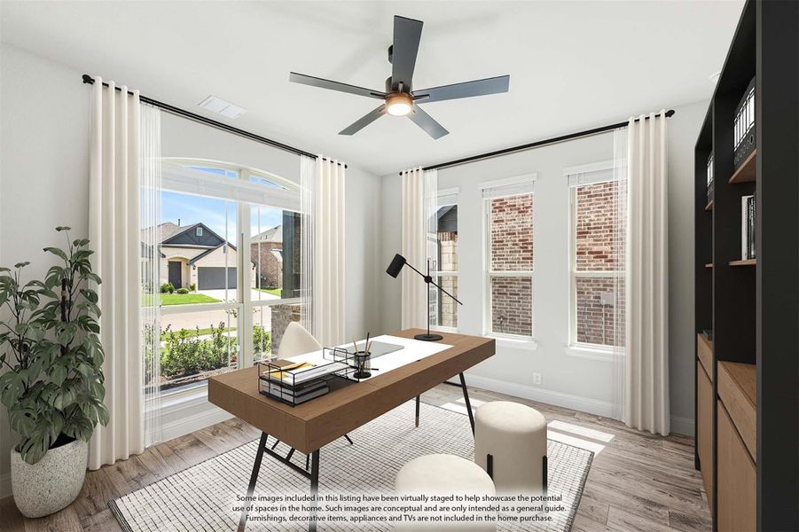 Home office with wood desk, ceiling fan, large windows, and light hardwood floors