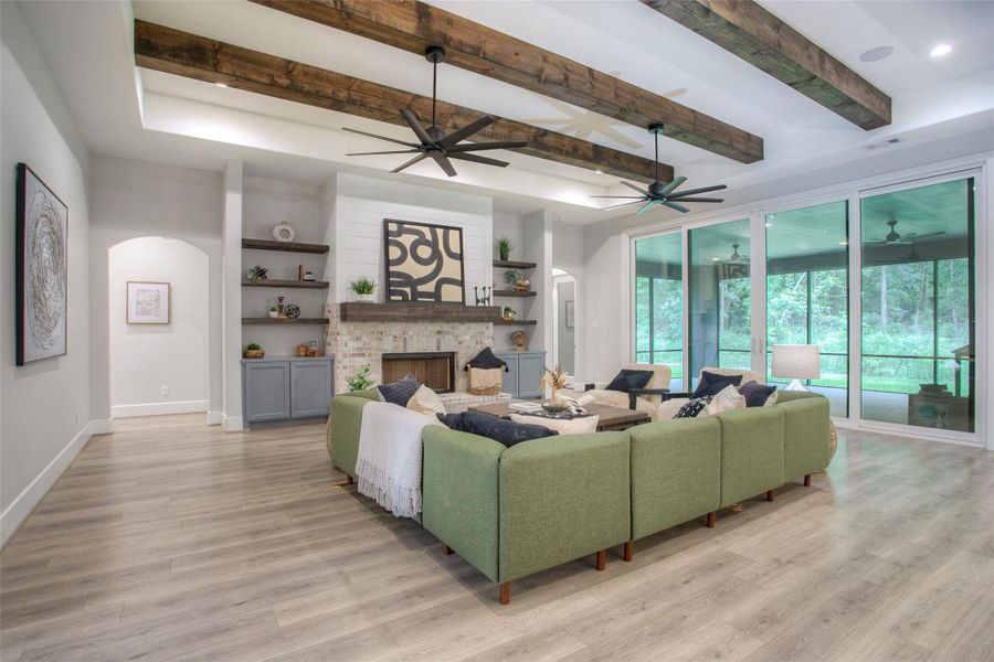 This spacious family room features modern design with exposed wooden beams, a lovely fireplace, and large sliding glass doors that open to a scenic view.