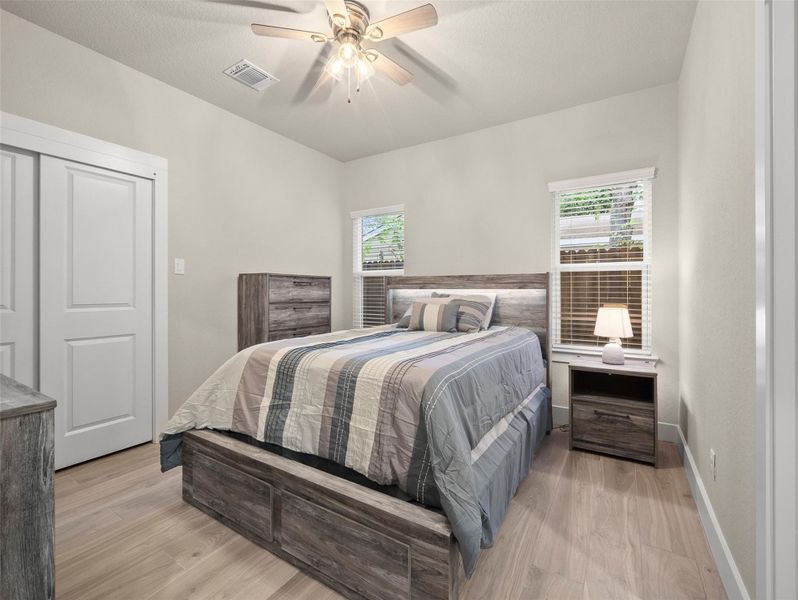 Bedroom with light wood-style flooring, multiple windows, and a ceiling fan Bedroom with light wood-style flooring, multiple windows, and a ceiling fan